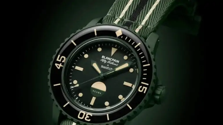 Swatch y Blancpain sorprenden de nuevo con una nueva versión de su reloj conjunto: el Swatch x Blancpain Green Abyss. Este modelo combina una paleta de colores de inspiración militar con las características del icónico reloj Fifty Fathoms, todo a un precio asequible. Cuando ellos Muestras y Blancpain lanzaron su primer reloj conjunto en 2023, muchos dudaron del éxito de esta inusual fusión. Pero con el tiempo, los escépticos se fueron acallando, y la colección Scuba Fifty Fathoms se convirtió en un verdadero éxito. Ahora, llega una nueva versión. Swatch x Blancpain Green Abyss – que promete ganarse los corazones de los amantes de los relojes con su estética militar y su precio asequible. Elegancia militar en verde Swatch x Blancpain Green Abyss Presenta un tono que Swatch llama "Verde Abismo", pero los expertos lo reconocerán como el clásico verde oliva militar (Verde OD). Este color fue el estándar en los uniformes militares estadounidenses de 1952 a 1989 y sigue siendo un símbolo de robustez y func